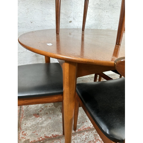 149 - A 1960s teak circular extending dining table and four teak and black vinyl dining chairs - table app... 