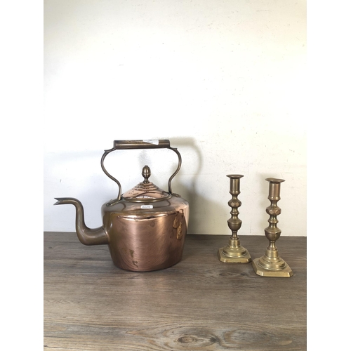 287 - Three pieces of metalware, two brass candlesticks and one Victorian copper kettle