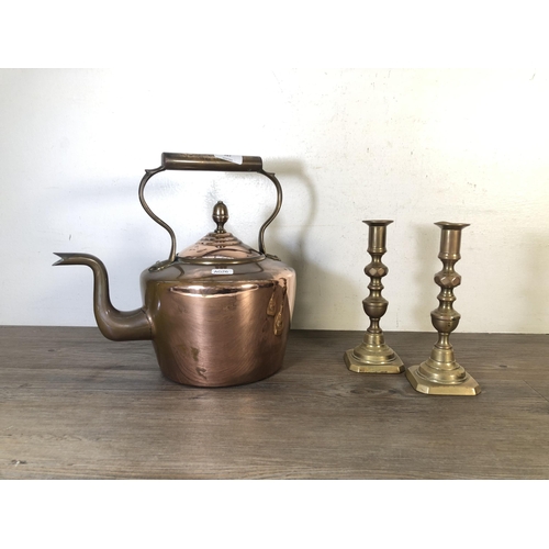 287 - Three pieces of metalware, two brass candlesticks and one Victorian copper kettle