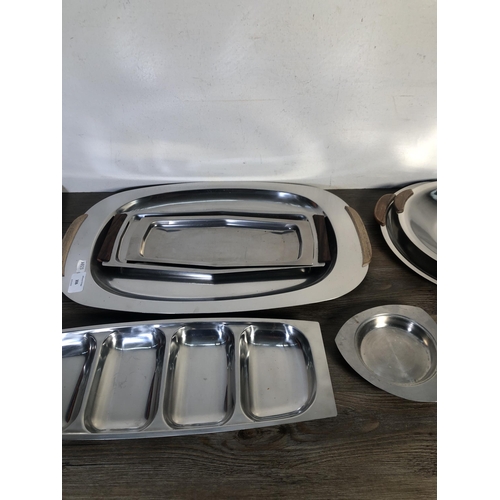 306 - Nine pieces of mid 20th century stainless steel kitchenware to include four teak handled trays etc.