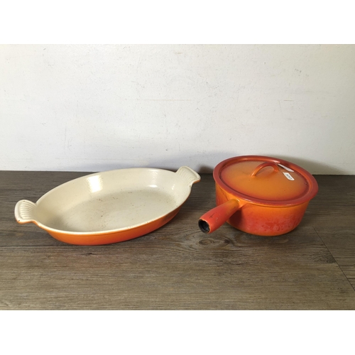 313 - Two pieces of orange enamel and cast iron kitchenware, one Le Creuset no.28 twin handled casserole d... 