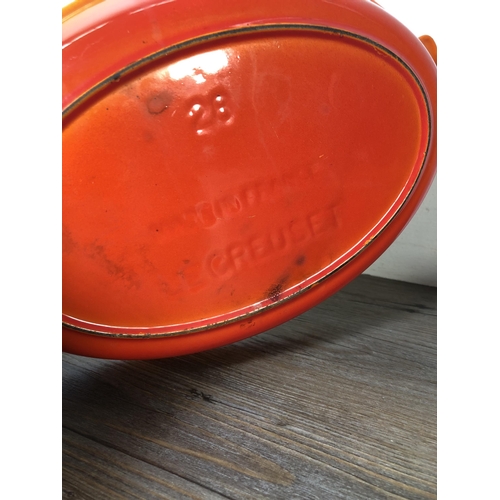 313 - Two pieces of orange enamel and cast iron kitchenware, one Le Creuset no.28 twin handled casserole d... 