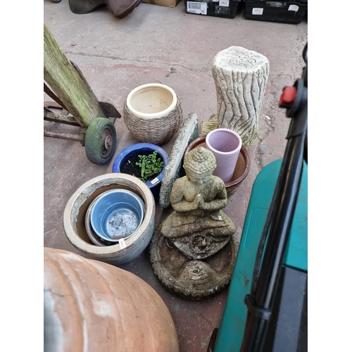 771 - A collection of planters and garden ornaments to include cast stone cherub holding wheatsheaf figure... 