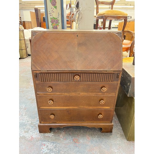 145 - A carved oak bureau with four drawers and fall front - approx. 102cm high x 76cm wide x 42cm deep