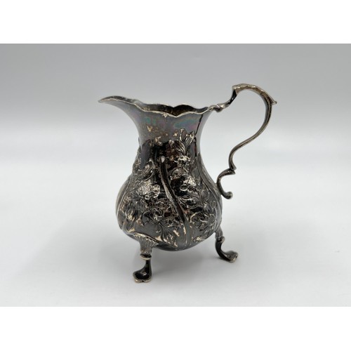 1168A - A George III John Muns hallmarked London silver repoussé tri footed milk jug, dated 1764 - approx. g... 