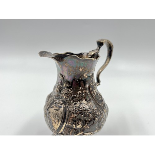 1168A - A George III John Muns hallmarked London silver repoussé tri footed milk jug, dated 1764 - approx. g... 