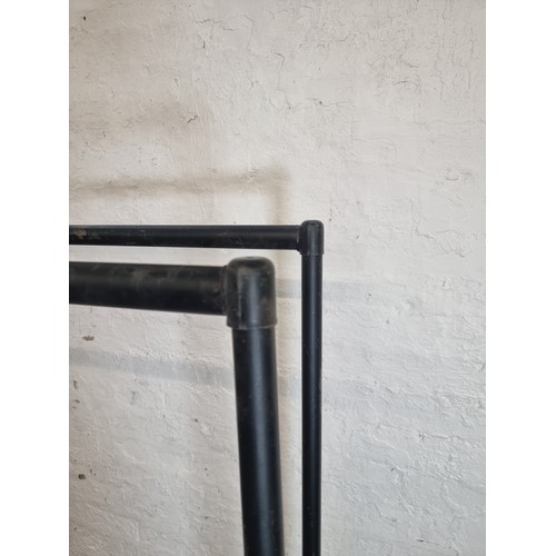 169A - Two black tubular metal clothes rails - largest approx. 158cm high x 182cm wide