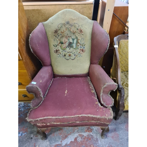 23 - An early/mid 20th century tapestry upholstered wing back armchair with cabriole supports