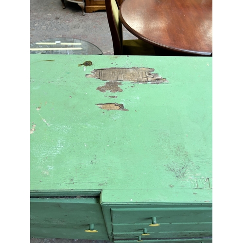 107 - A mid 20th century green painted sideboard with four central drawers and two outer cupboard doors