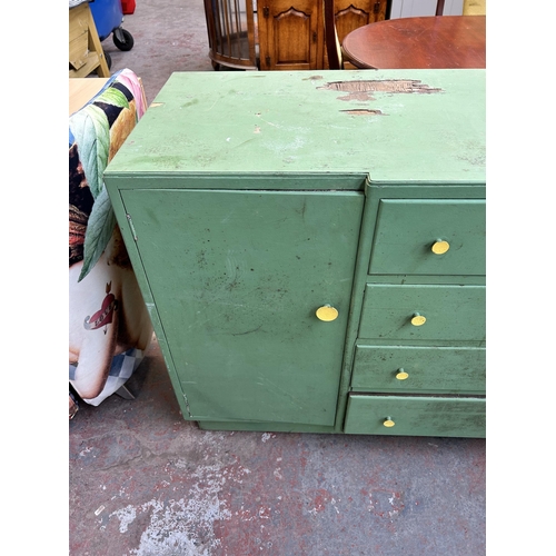 107 - A mid 20th century green painted sideboard with four central drawers and two outer cupboard doors