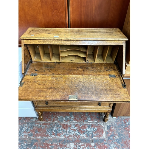 152 - An early 20th century oak bureau with three drawers, fall front and barley twist supports - approx. ... 