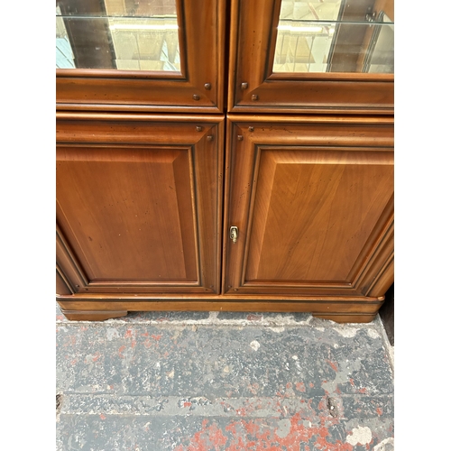 167 - A French style cherry wood display cabinet with two upper bevelled glass doors and two internal glas... 