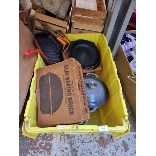 902 - A box containing kitchenware to include two Le Creuset style grey enamel and cast iron lidded casser... 