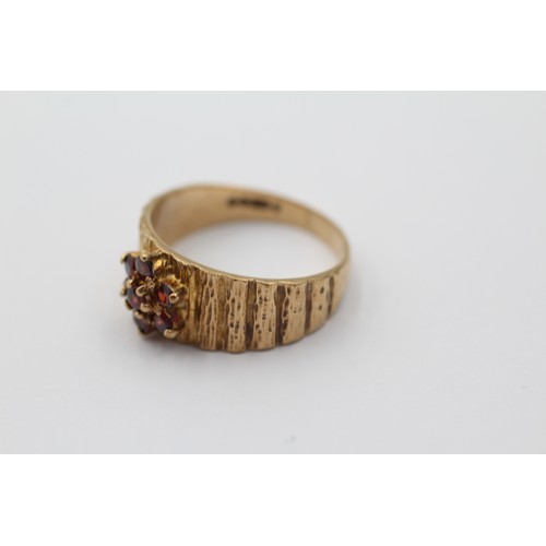 1098 - A 9ct gold garnet floral cluster ring with textured shank, size N - approx. gross weight 3.4 grams