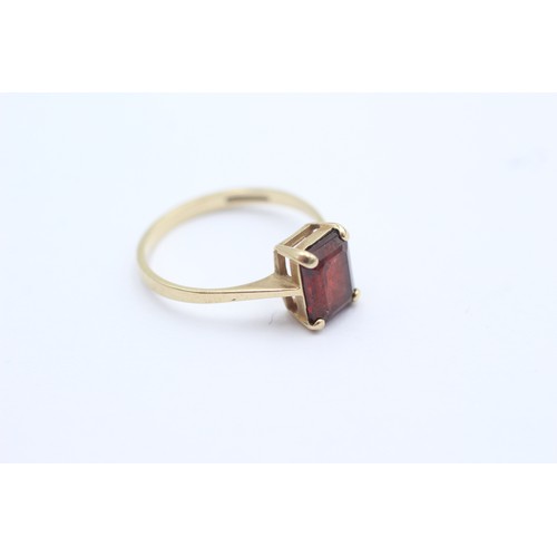 1102 - A 9ct gold baguette cut garnet solitaire ring, size N½ - approx. gross weight 1.8 grams