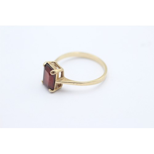 1102 - A 9ct gold baguette cut garnet solitaire ring, size N½ - approx. gross weight 1.8 grams