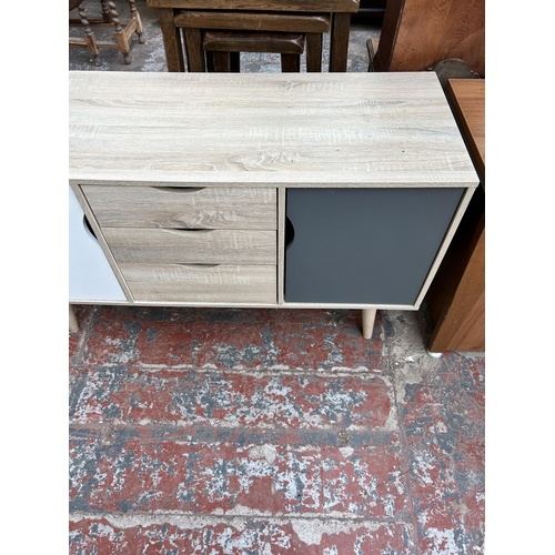 109 - An LPD Scandi oak effect sideboard with two white and grey painted cupboard doors and three central ... 