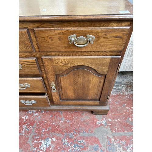 111 - A Georgian style oak sideboard with six drawers and two cupboard doors