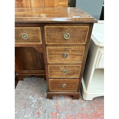 114 - An Edwardian inlaid mahogany kneehole writing desk with nine drawers and central cupboard door