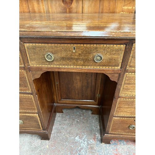 114 - An Edwardian inlaid mahogany kneehole writing desk with nine drawers and central cupboard door