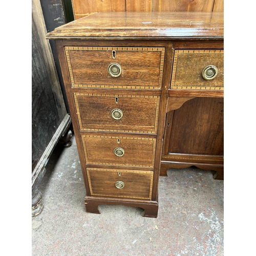 114 - An Edwardian inlaid mahogany kneehole writing desk with nine drawers and central cupboard door