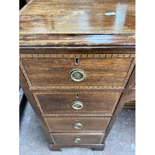 114 - An Edwardian inlaid mahogany kneehole writing desk with nine drawers and central cupboard door