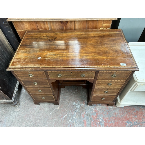 114 - An Edwardian inlaid mahogany kneehole writing desk with nine drawers and central cupboard door