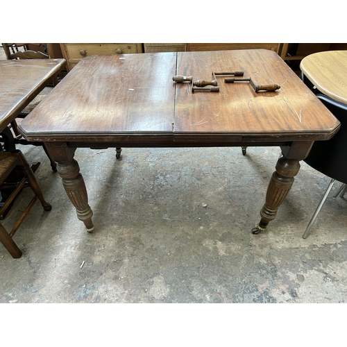 2 - A Victorian mahogany wind out dining table with reeded supports and original castors