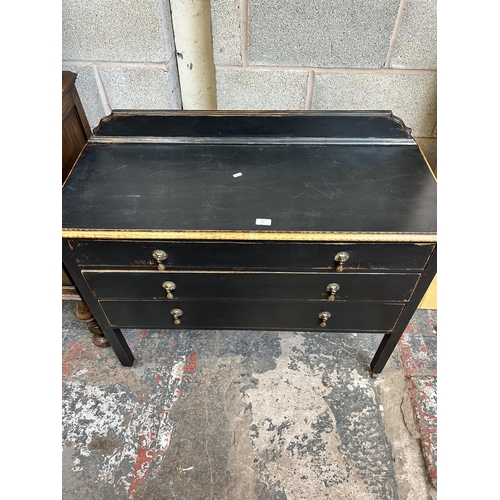 21 - An early 20th century black painted oak chest of three drawers