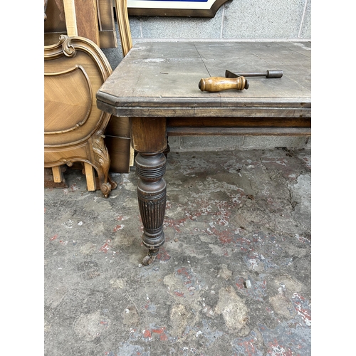 25 - A Victorian mahogany wind out dining table with reeded supports and castors