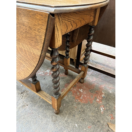 29 - An early/mid 20th century oak drop leaf gate leg oval dining table on barley twist supports