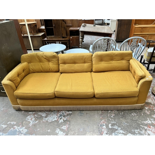 33 - A mid 20th century yellow fabric upholstered three seater sofa