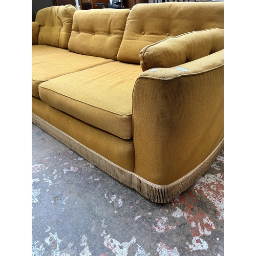 33 - A mid 20th century yellow fabric upholstered three seater sofa