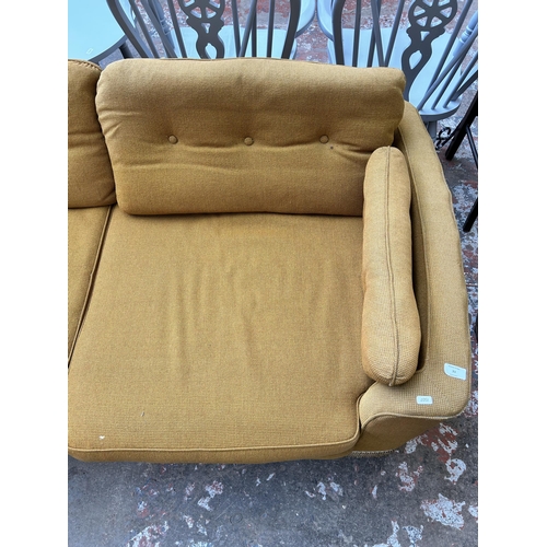 33 - A mid 20th century yellow fabric upholstered three seater sofa