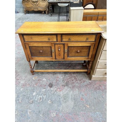 60 - An early 20th century oak sideboard with beaded decoration and barley twist supports