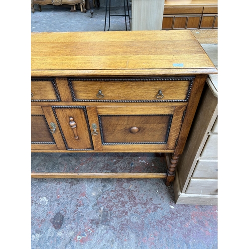 60 - An early 20th century oak sideboard with beaded decoration and barley twist supports