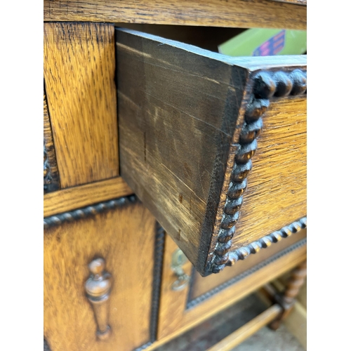 60 - An early 20th century oak sideboard with beaded decoration and barley twist supports