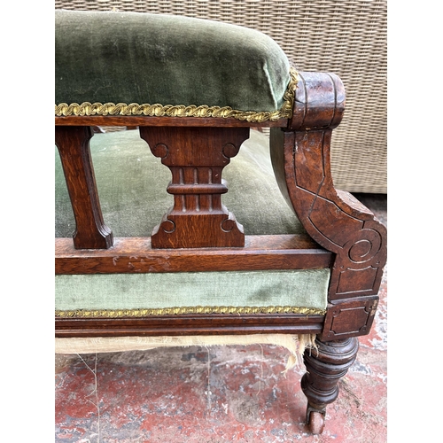 162 - A Victorian oak and green fabric upholstered armchair on castors