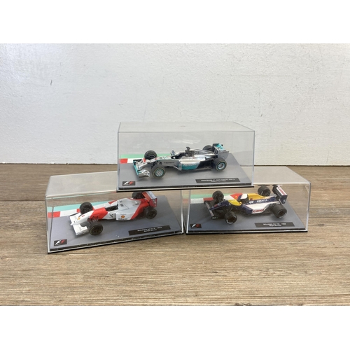 326 - A wooden display case containing twenty seven boxed Formula 1 model racing cars - display case appro... 