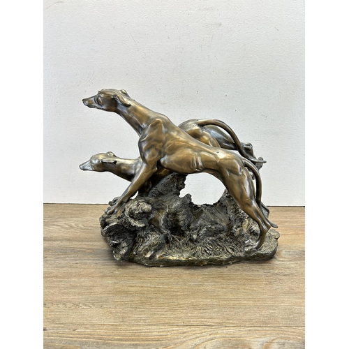 545 - A modern bronze effect figurine of two sighthounds - approx. 31cm high x 38cm long