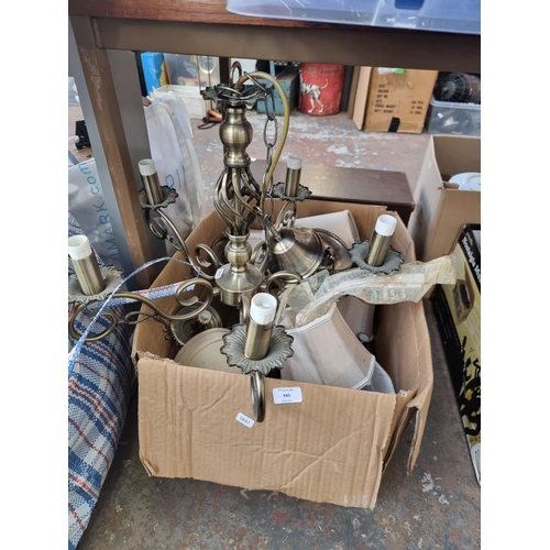 945 - A box containing lighting items to include brass effect chandelier, lampshade etc.