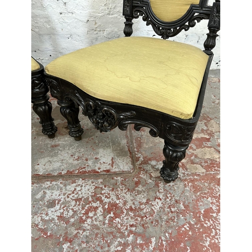 100 - A pair of Victorian ebonised low seated hall chairs