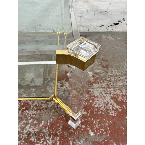 108 - A 1980s Hollywood Regency style lucite and brass effect square coffee table with two bevelled glass ... 