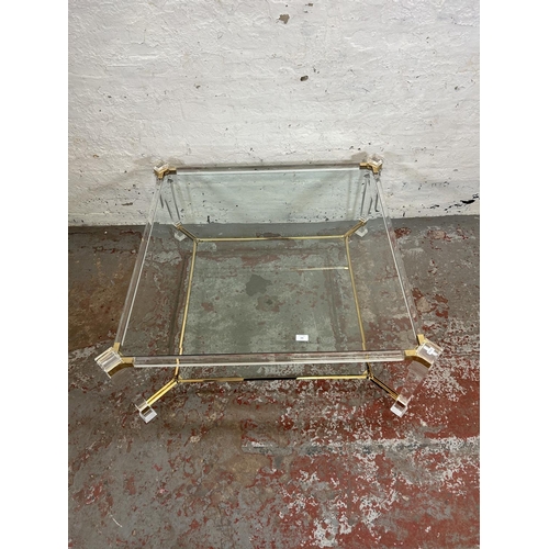 108 - A 1980s Hollywood Regency style lucite and brass effect square coffee table with two bevelled glass ... 