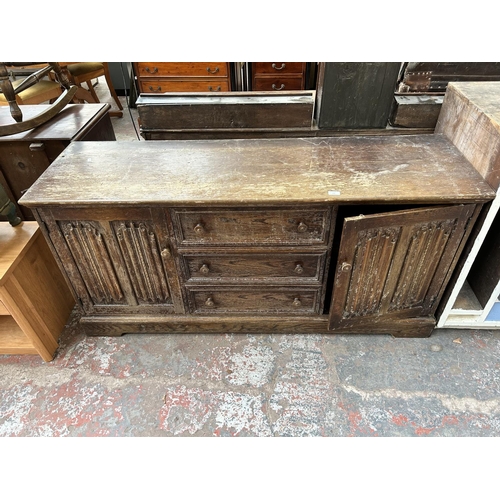 170 - An oak sideboard with three central drawers and two outer linenfold cupboard doors - top measuring a... 