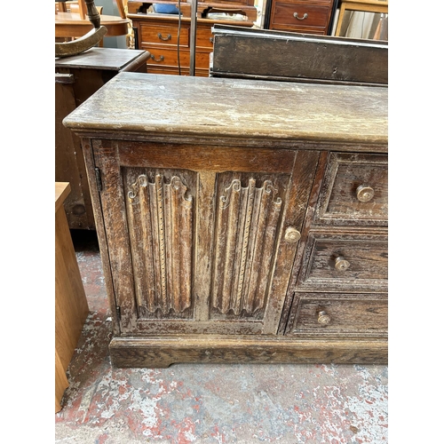 170 - An oak sideboard with three central drawers and two outer linenfold cupboard doors - top measuring a... 