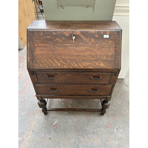 175 - A 1930s oak bureau with two drawers, fall front and baluster supports