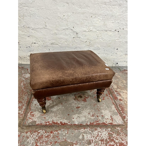 213 - A 19th century style brown leatherette footstool with mahogany supports and brass castors