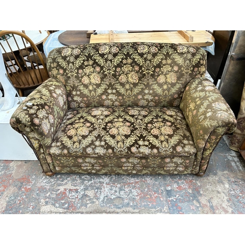 217 - A 1930s floral upholstered drop arm sofa on mahogany supports and castors