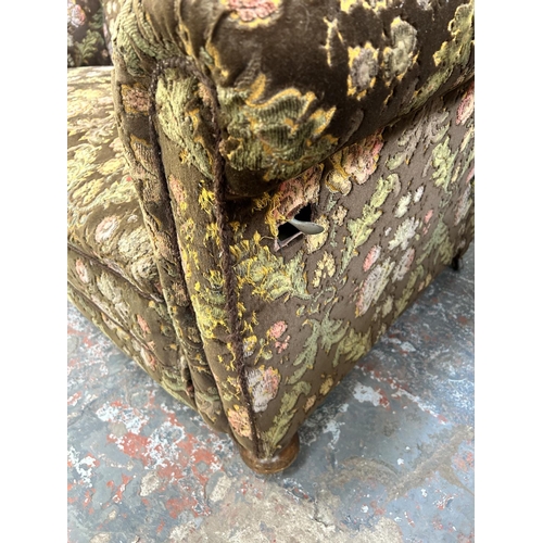 217 - A 1930s floral upholstered drop arm sofa on mahogany supports and castors